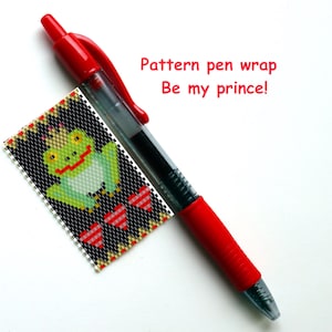 Könnte beinhalten: Ein roter und durchsichtiger Stift neben einem kleinen, rechteckigen Muster mit einem pixeligen Frosch, der eine Krone trägt. Das Muster ist schwarz mit roten, weißen und gelben Akzenten. Der Text auf dem Bild lautet "Pattern pen wrap Be my prince!"