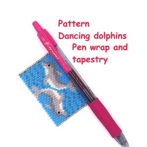 May include: A pink Pilot G-2 07 pen rests on a beaded tapestry featuring two gray dolphins on a blue background. The tapestry is rectangular and has a beaded border. Text on the image reads "Pattern Dancing dolphins Pen wrap and tapestry."