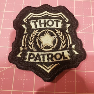 May include: Embroidered black and white patch in the shape of a badge. The patch features the words "THOT PATROL" in a banner, with a star and laurel wreath design.