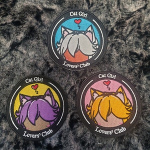 May include: Three round embroidered patches with a cat-themed design. Each patch features a cat girl illustration with different hair colors: white, purple, and orange. The text "Cat Girl" and "Lovers' Club" are included.