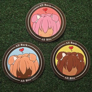 Peut inclure: Trois autocollants ronds avec des illustrations de chiens de dessin animé. Chaque autocollant présente une palette de couleurs différente : rose, marron et marron foncé. Le texte "All Bark" et "All Bite" est imprimé sur chaque autocollant.