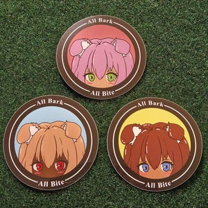 Peut inclure: Trois dessous de verre ronds avec des illustrations de chiens de style anime. Chaque dessous de verre présente un chien de couleur différente avec le texte "All Bark" et "All Bite". Les chiens ont des cheveux roses, bruns et brun foncé.
