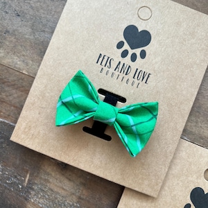May include: Green and white plaid bow tie on a brown card with the text "Pets and Love Boutique".