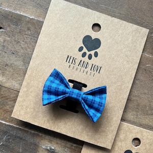 May include: A blue and white plaid bow tie on a brown card with the text "Pets and Love Boutique".