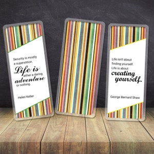May include: Three rectangular cards with inspirational quotes. Each card features a colourful striped pattern and a white section with text. The quotes are from Helen Keller and George Bernard Shaw. The cards are on a wooden surface.