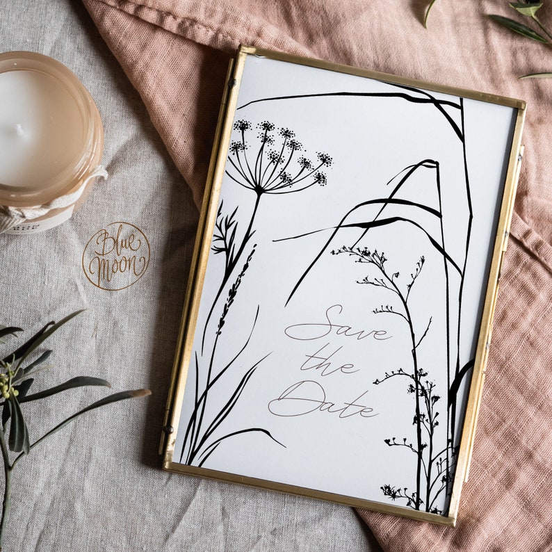May include: A gold-framed print with a black and white illustration of wildflowers and the text "Save the Date".