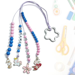 Może przedstawiać: Zestaw trzech koralikowych sznurków z zawieszkami. Każdy sznurek ma inną zawieszkę: jednorożca, konika morskiego i syrenę. Sznurki są wykonane z różowych i niebieskich koralików oraz srebrnej zawieszki z napisem "NAME".