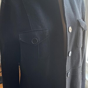 May include: A black, long-sleeved jacket with a mandarin collar, three buttons, and two flap pockets.
