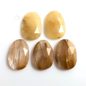May include: Six faceted, oval-shaped, translucent stones with a golden brown colour. The stones have a striated pattern and are arranged in two rows of three.