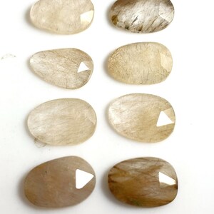 May include: Eight natural, oval-shaped, translucent, light brown, and white stones with a rough, textured surface.
