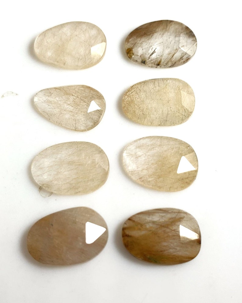 May include: Eight natural, oval-shaped, translucent, light brown, and white stones with a rough, textured surface.