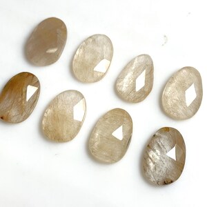 May include: Eight translucent, oval-shaped, light brown stones with a white diamond shape in the center.