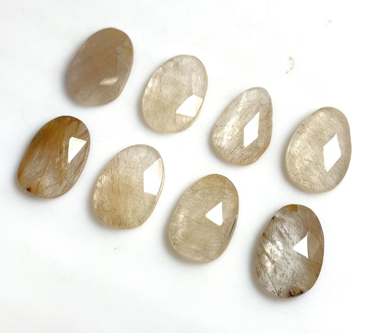 May include: Eight translucent, oval-shaped, light brown stones with a white diamond shape in the center.