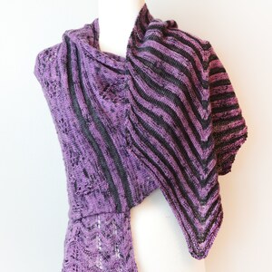 May include: A purple and black striped knitted shawl with a lacy trim. The shawl is draped over a white mannequin.