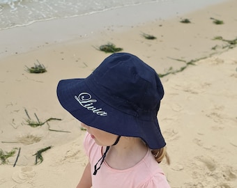 May include: A navy blue sun hat with a wide brim and a white embroidered name "Livia" on the front.