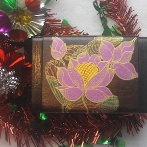 May include: A wooden box featuring a hand-painted design of pink and yellow lotus flowers on a dark brown background.