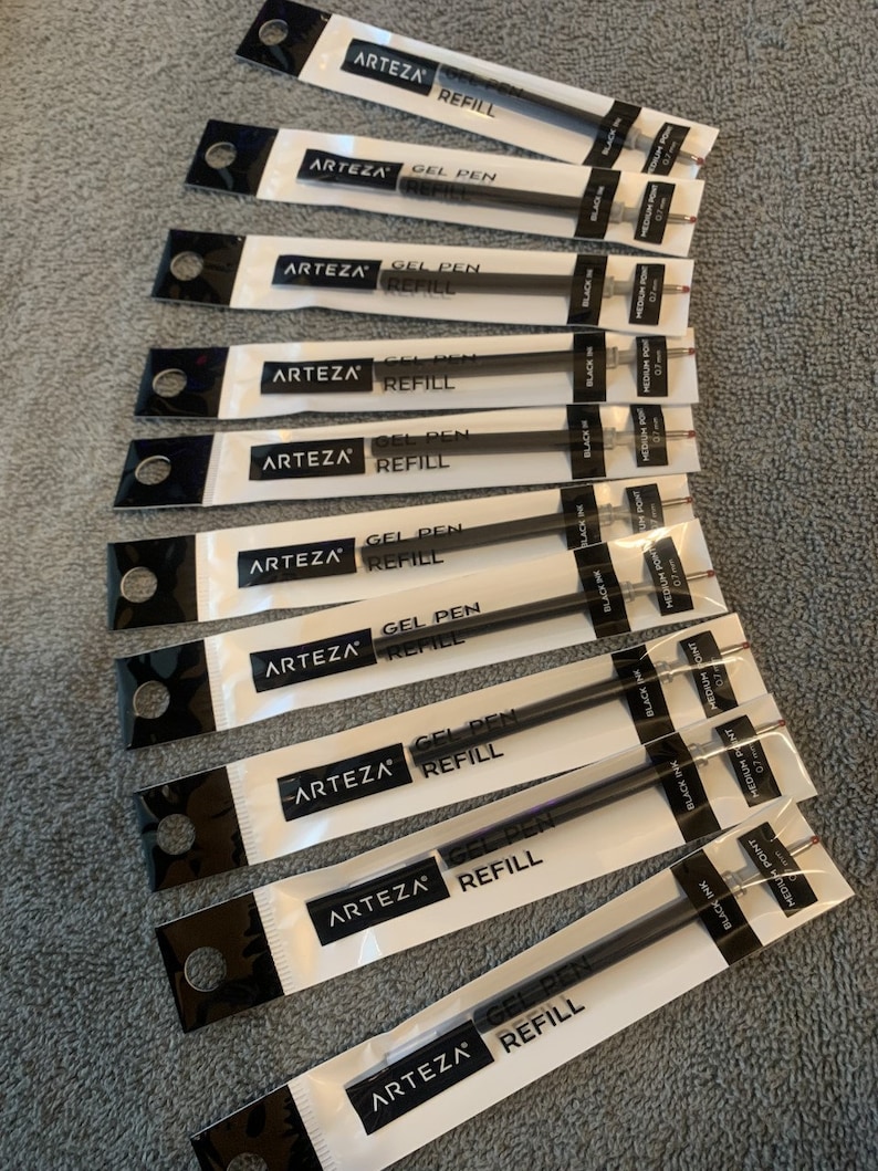 K&ouml;nnte beinhalten: Ein Stapel von zehn schwarzen Gel-Stiftminen, verpackt in durchsichtigen Plastikverpackungen mit dem Markennamen "ARTEZA" und dem Text "GEL PEN REFILL" auf jeder Verpackung. Die Minen sind mit "BLACK INK" und "MEDIUM POINT 0.7" beschriftet.