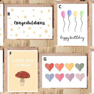 May include: A collection of greeting cards with various designs and messages. Cards include "Good Luck", "Congratulations", "Happy Birthday", and "Get Well Soon". Other cards feature watercolor illustrations of balloons, hearts, a mushroom, a moon, and trees. Each card has a brown border.