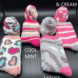 May include: Assortment of fuzzy socks in various patterns and colors. Designs include leopard print, stripes, and a mouse-like pattern. Colors include pink, gray, white, and teal. Text on the image reads "Strawberries & Cream", "Cool Mint", and "Mouse".