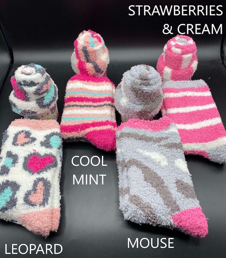 May include: Assortment of fuzzy socks in various patterns and colors. Designs include leopard print, stripes, and a mouse-like pattern. Colors include pink, gray, white, and teal. Text on the image reads "Strawberries & Cream", "Cool Mint", and "Mouse".