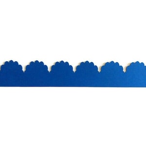 May include: A strip of blue paper with a scalloped edge. The paper is a solid, vibrant blue color and is set against a plain white background. The scalloped edge creates a decorative border.