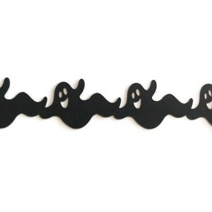 May include: Black and white silhouette of a row of ghosts with smiling faces. The ghosts are cut out of paper and are arranged in a wavy line.