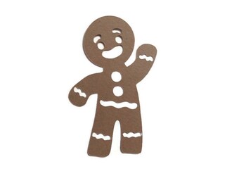 May include: A brown gingerbread man cutout featuring white die-cut details including a smiling face, two circular buttons on the chest, and wavy lines across the arms and legs. The figure is depicted with one arm raised in a waving gesture.