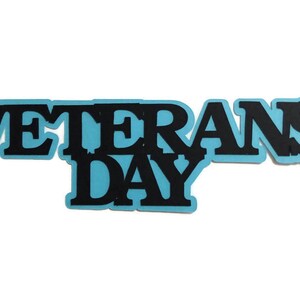 May include: Blue and black paper cutout of the words "Veterans Day".
