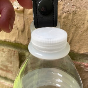 May include: A black and red bottle holder with a Mickey Mouse design. The holder is attached to a clear plastic water bottle.
