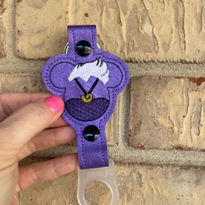 May include: Purple fabric key chain with a cartoon character's head, a clear plastic bottle holder, and a black button.
