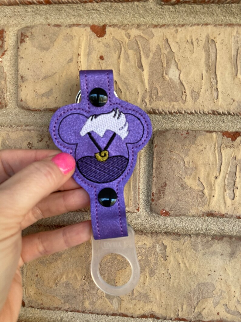 May include: Purple fabric key chain with a cartoon character's head, a clear plastic bottle holder, and a black button.