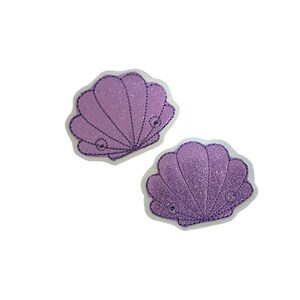May include: Two purple glitter seashell patches with white outlines. The seashells are embroidered with a detailed design.
