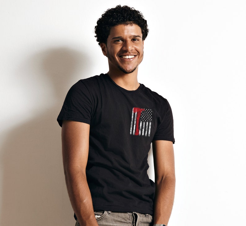 May include: A man wearing a black t-shirt with a red, white, and blue American flag graphic on the front. The flag is distressed and has a red axe superimposed on it.