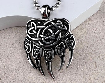 May include: Silver bear paw pendant necklace with a Celtic knot design. The pendant is detailed with intricate knotwork and has a textured finish.