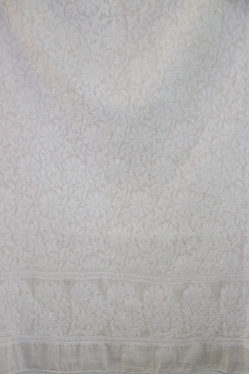 May include: White cotton fabric with a delicate floral pattern. The fabric has a subtle sheen and a soft texture.