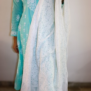 May include: A white embroidered cotton dupatta with a delicate floral pattern. The dupatta is draped over a light blue dress with white embroidery.