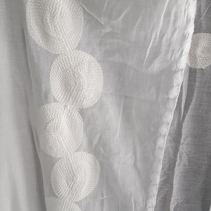 May include: White sheer fabric with a decorative border of white embroidered circles.
