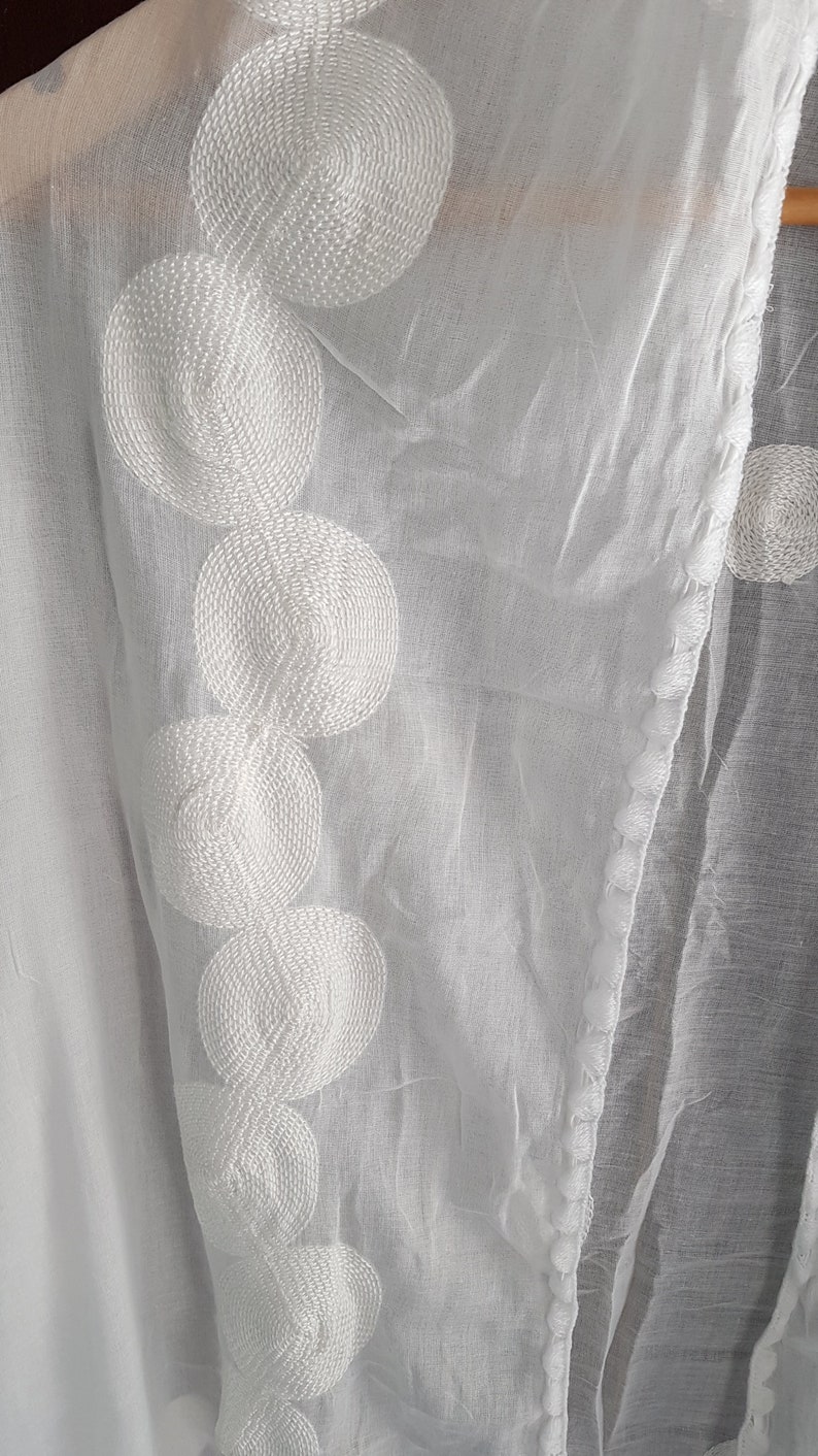 May include: White sheer fabric with a decorative border of white embroidered circles.