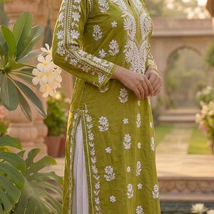 Puede incluir: Kurta bordada en verde oliva con detalles florales blancos. La t&uacute;nica de manga larga se combina con pantalones blancos. El atuendo se usa con sandalias doradas. La ropa es adecuada para ocasiones informales o formales.