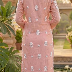 Puede incluir: Una kurta rosa claro bordada con patrones florales blancos. La t&uacute;nica de manga larga se combina con pantalones blancos. El conjunto forma parte de un estilo indio tradicional, perfecto para uso casual o festivo.