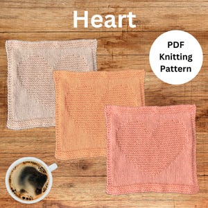 May include: Three knitted heart-shaped dishcloths in beige, orange, and pink. The dishcloths are laid out on a wooden surface. PDF Knitting Pattern.