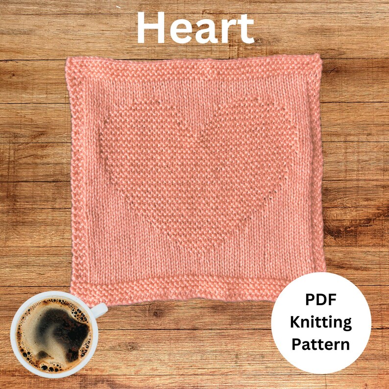 May include: A pink knitted heart-shaped square with a PDF knitting pattern label. The square is on a wooden surface.