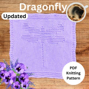Puede incluir: Un paño de cocina de punto morado con un diseño de libélula. El paño de cocina está sobre una superficie de madera con una taza de café y flores. El texto "Dragonfly" y "Updated" es visible. El texto "PDF Knitting Pattern" también es visible.