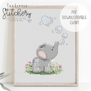 May include: Cross stitch pattern featuring a cute gray elephant blowing heart-shaped bubbles. The pattern is surrounded by a floral border and includes the text "The Little Stitchery".