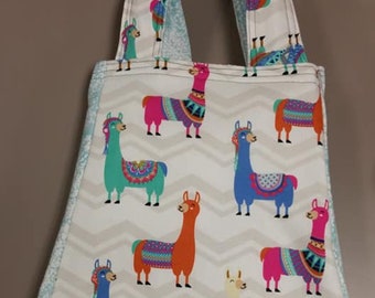 May include: A white tote bag with a chevron pattern and colorful llama illustrations. The bag has two blue and white fabric handles.