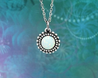 Puede incluir: Un collar de cadena de plata con un colgante de ópalo blanco engastado en un bisel de plata con un borde de cuentas.