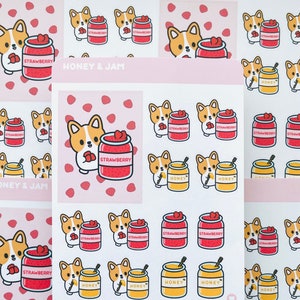 May include: A sheet of stickers featuring a cartoon corgi dog holding jars of honey and strawberry jam. The stickers have a pink background with white polka dots. The text "HONEY & JAM" is printed at the top of the sheet.