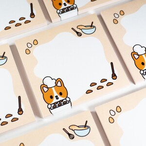 May include: A set of 10 pastel orange sticky notes featuring a cartoon corgi wearing a chef's hat and holding a baking sheet of cookies. The notes also include illustrations of a whisk, bowl of batter, and scattered cookie dough.