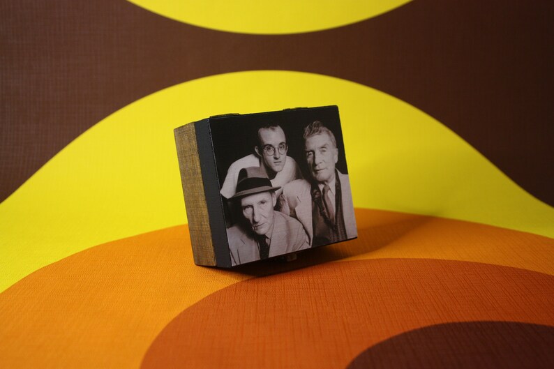 May include: A wooden box with a black and white photo of three men. The men are wearing hats and suits. The box is sitting on a brown and yellow patterned surface.