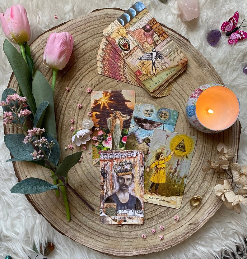 May include: A collection of tarot cards with vintage-style illustrations, including a card with the text "IV - Leadership". The cards are arranged on a wooden slice with flowers, crystals, and a lit candle, creating a mystical aesthetic.